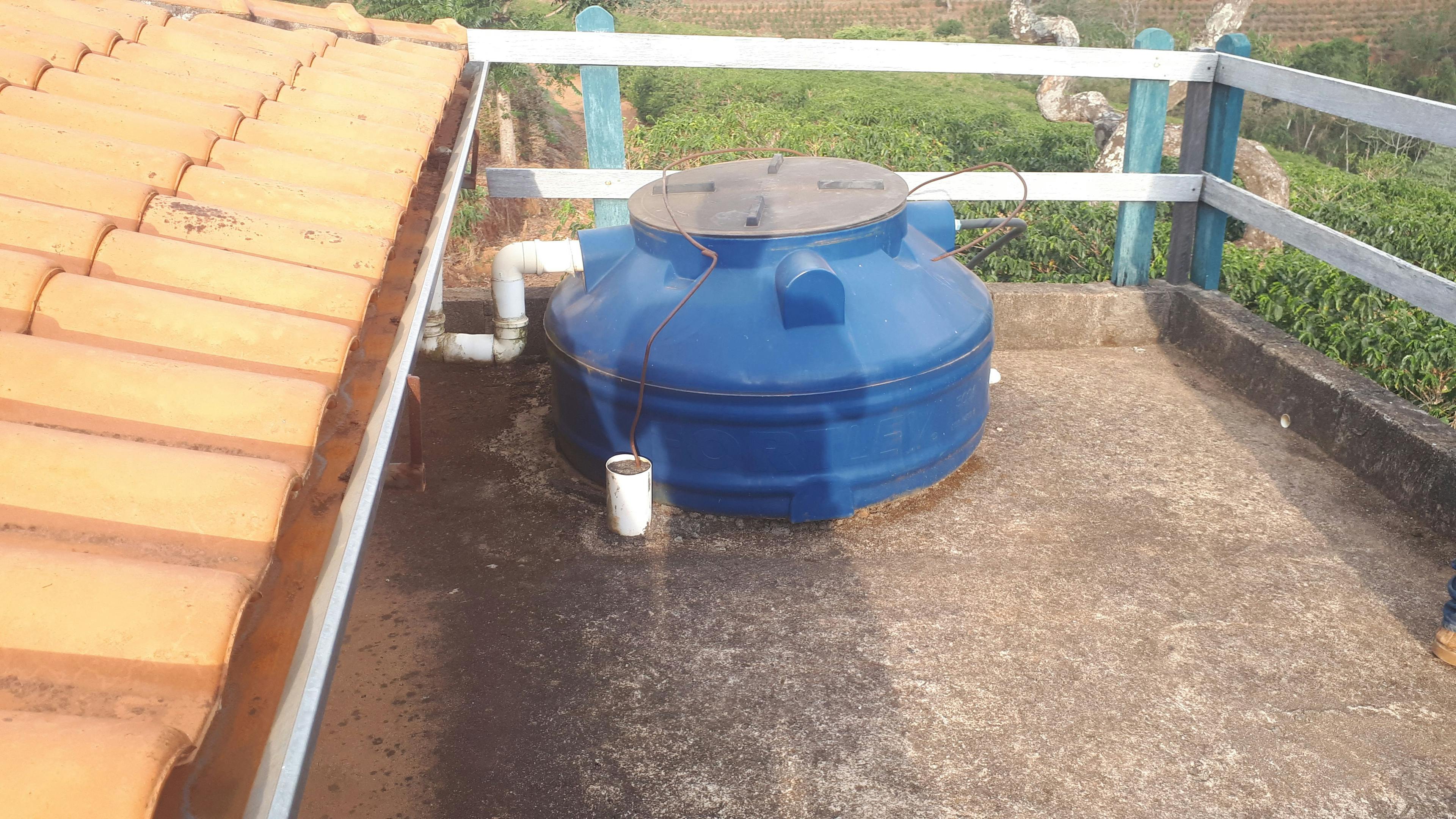 a blue water tank is sitting on top of a roof next to a gutter .