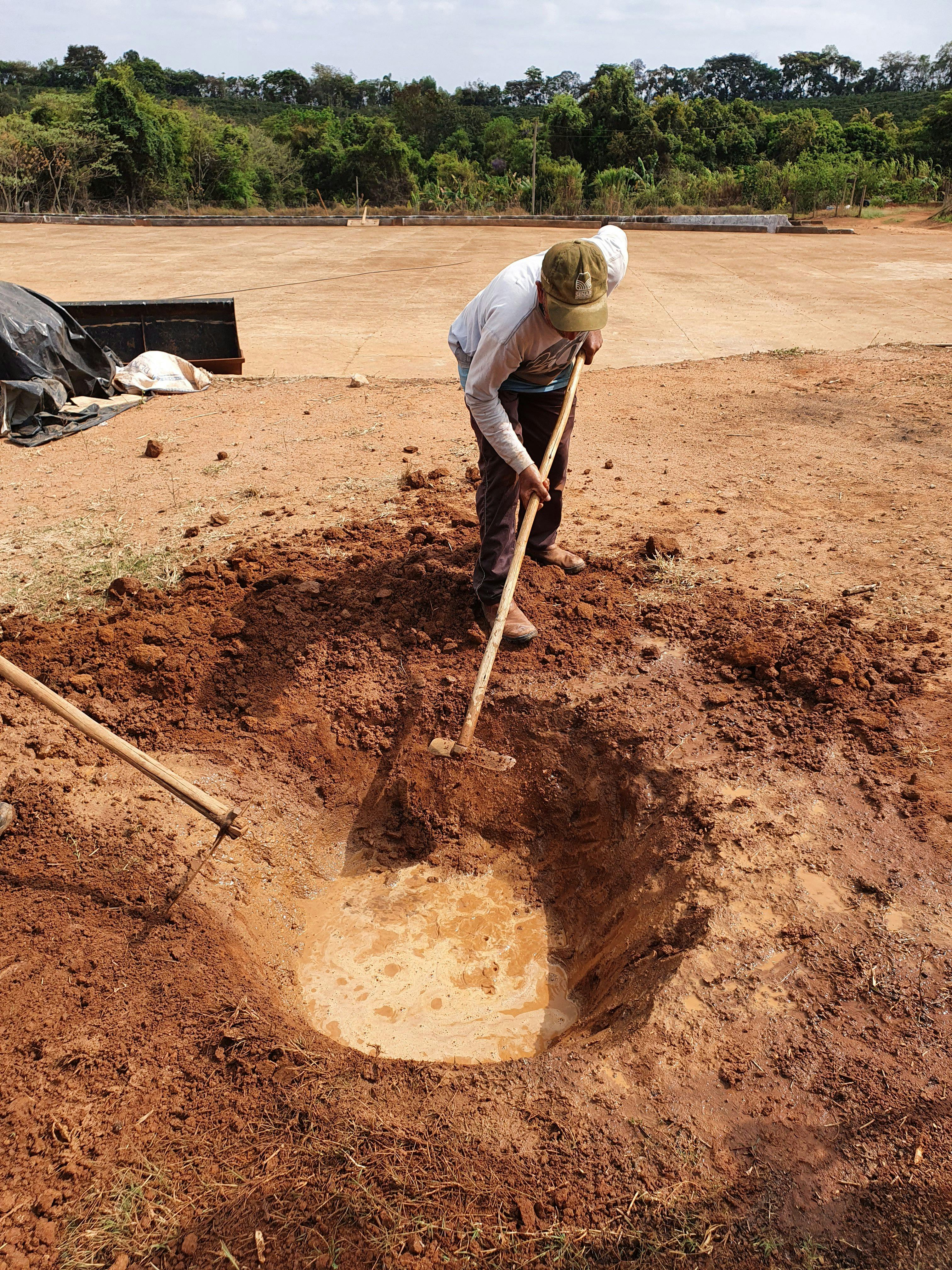 a man is digging a hole in the dirt with a shovel .