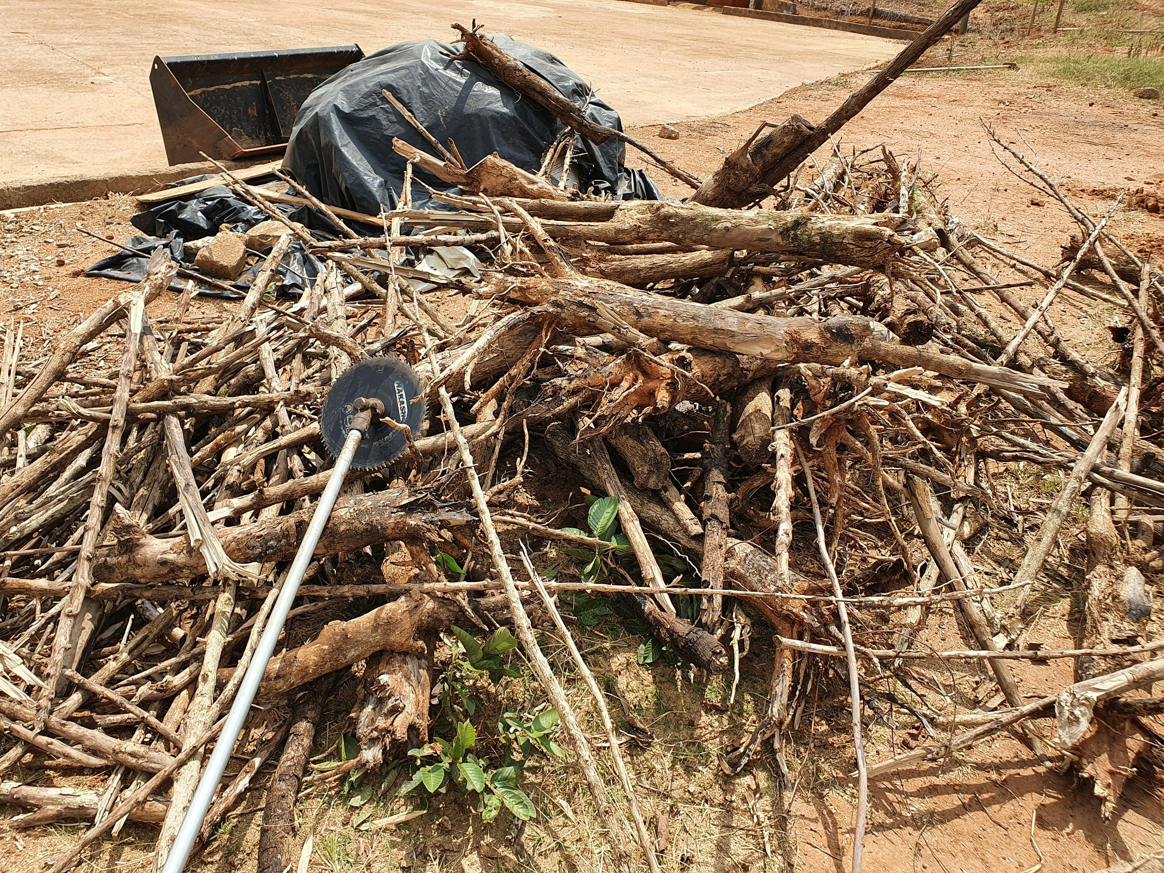 a pile of wood is sitting on the ground next to a black tarp .