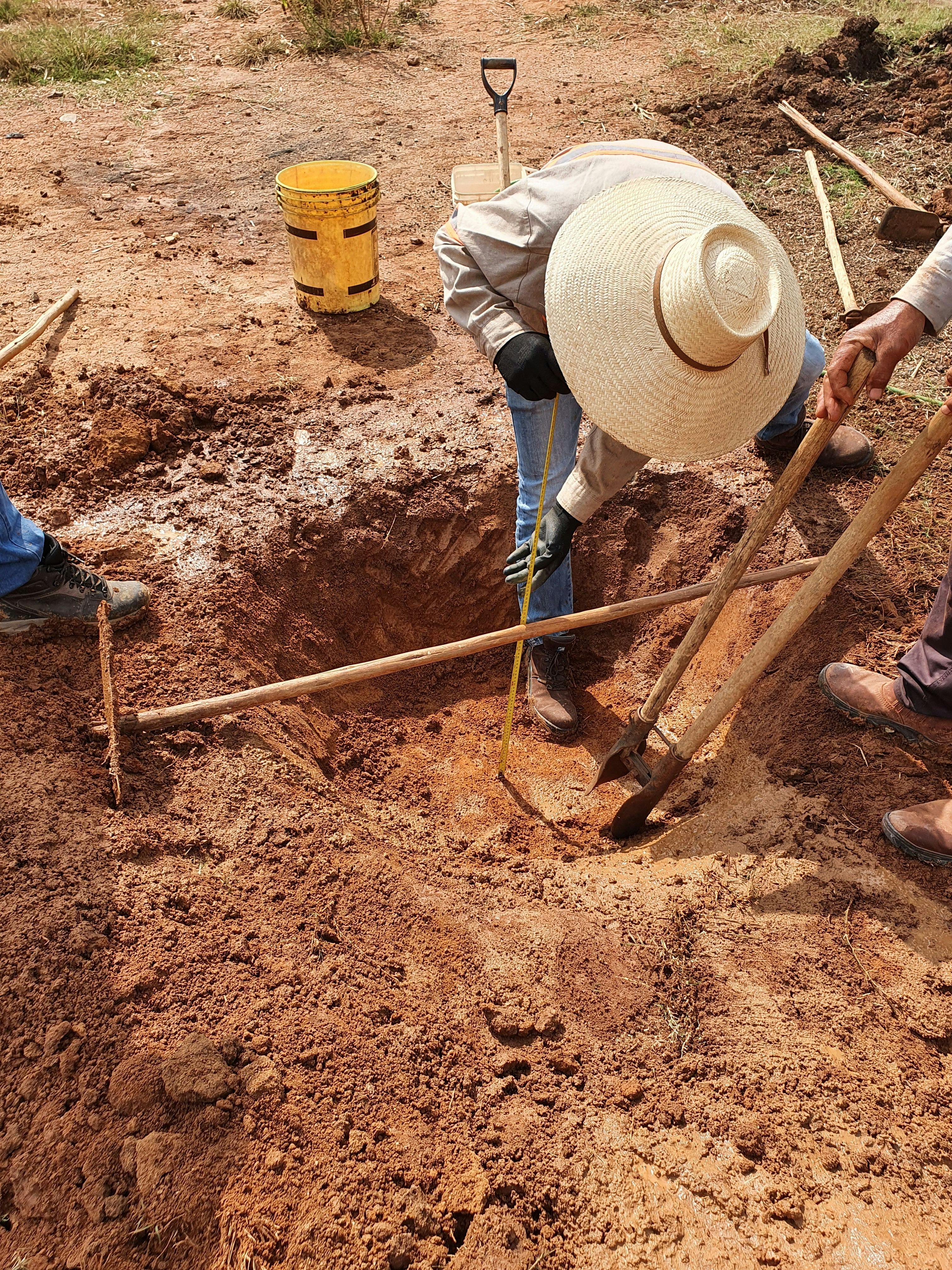 a man in a hat is measuring a hole in the ground