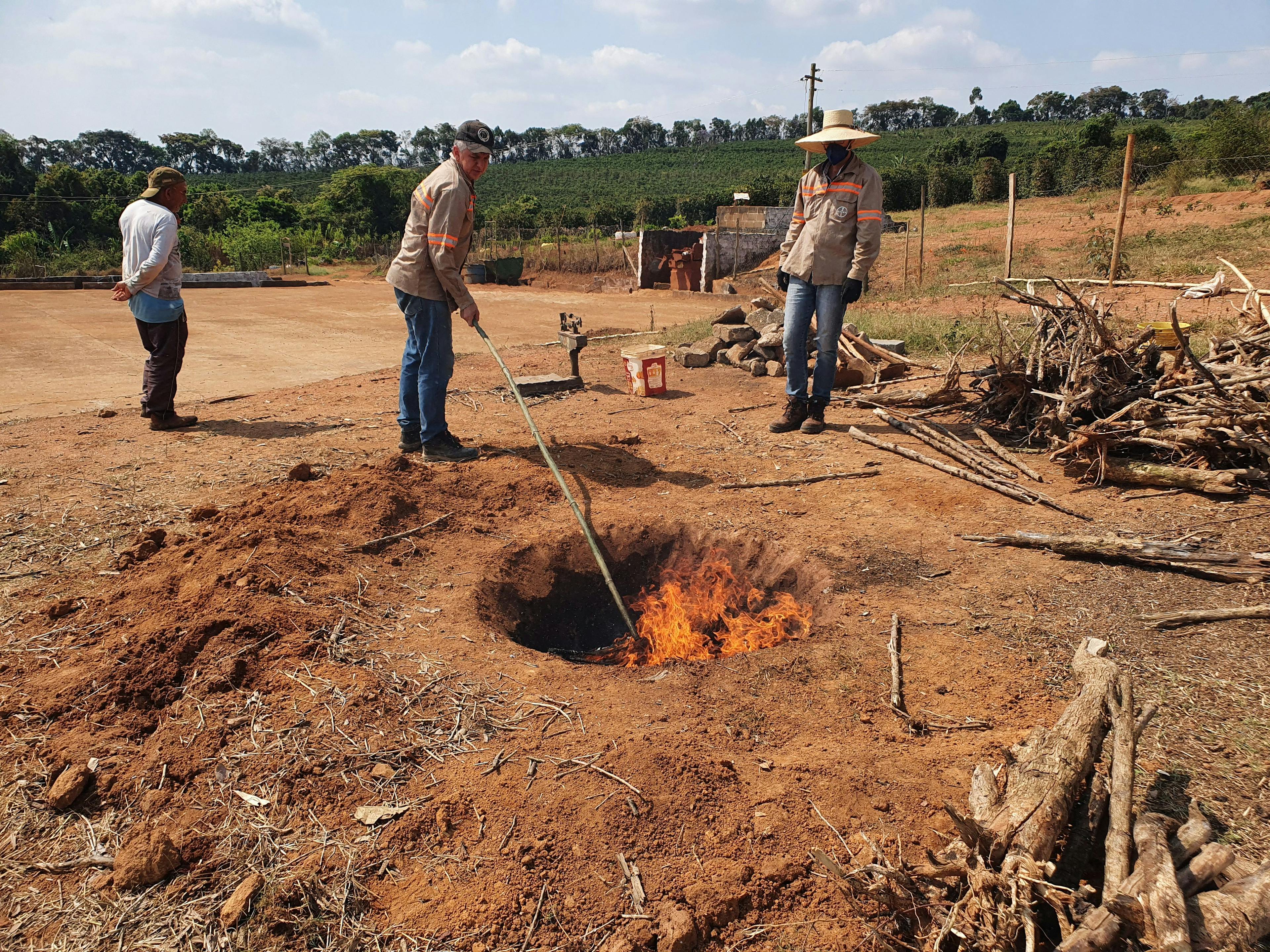 two men are standing around a fire in the dirt .