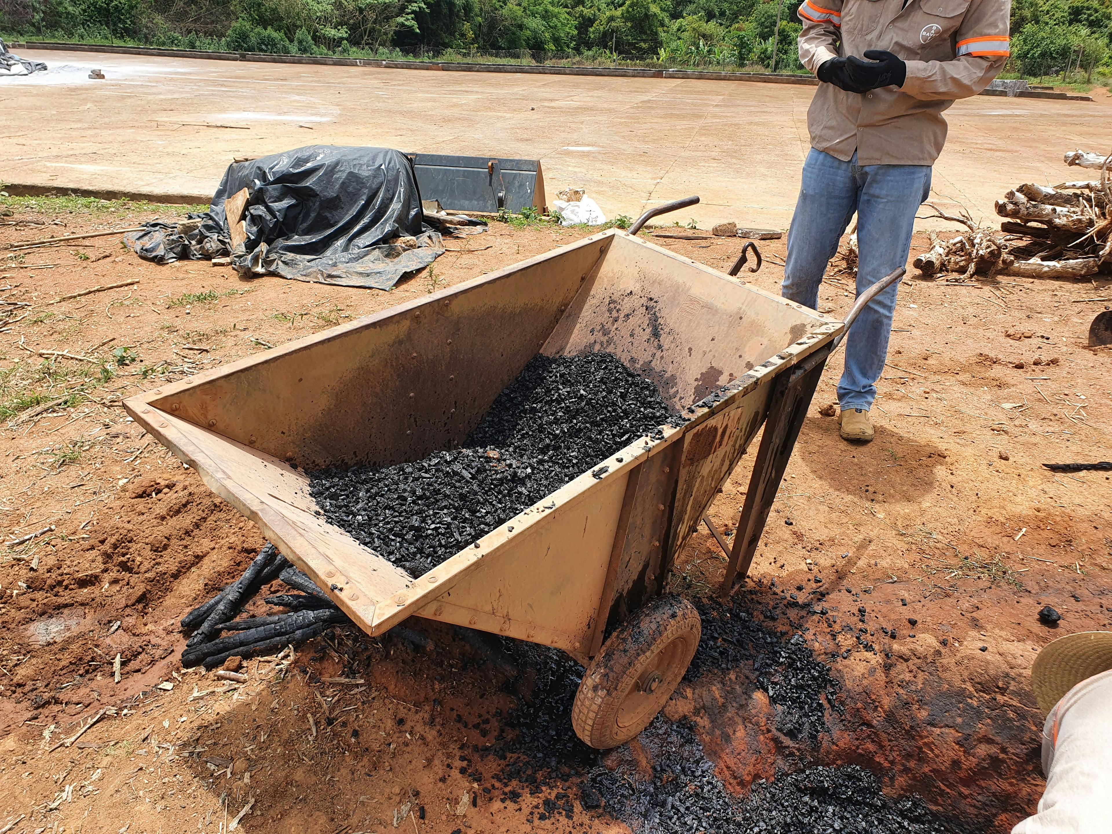 a man is standing next to a wheelbarrow filled with ashes .