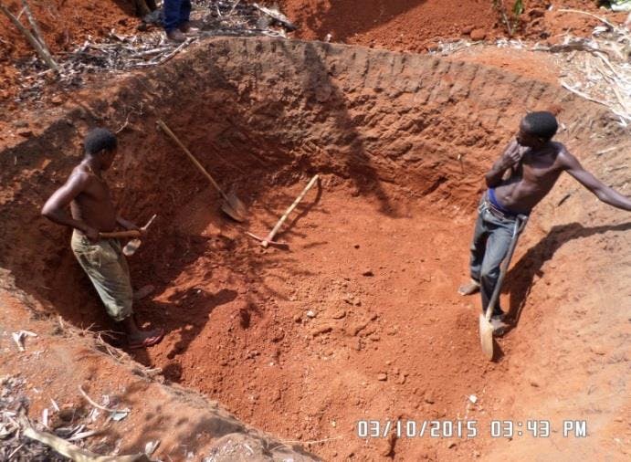 a photo of two men digging a hole 