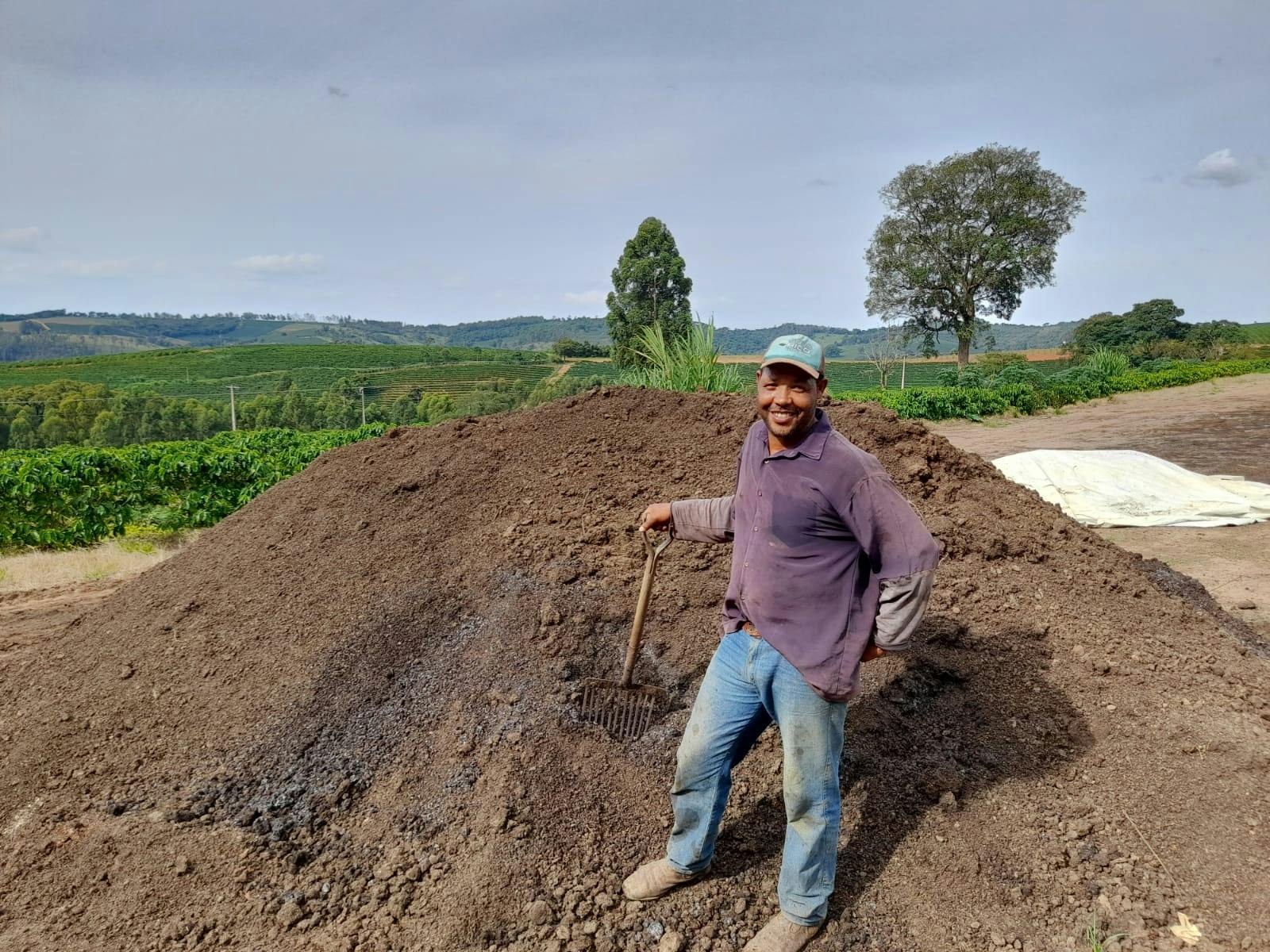 a man is standing next to a pile of dirt with a rake .