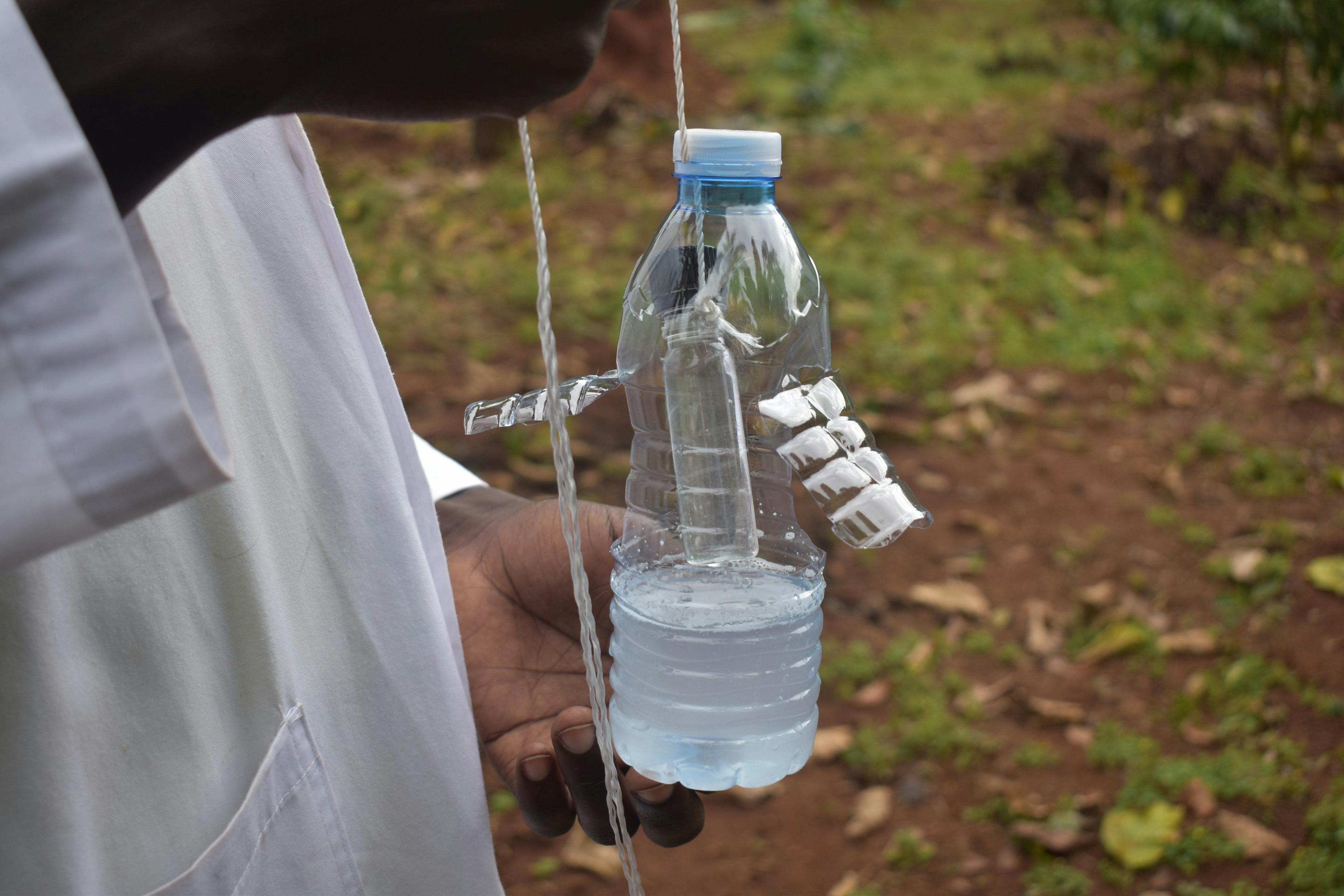 a person is holding a bottle of water with a rope attached to it .