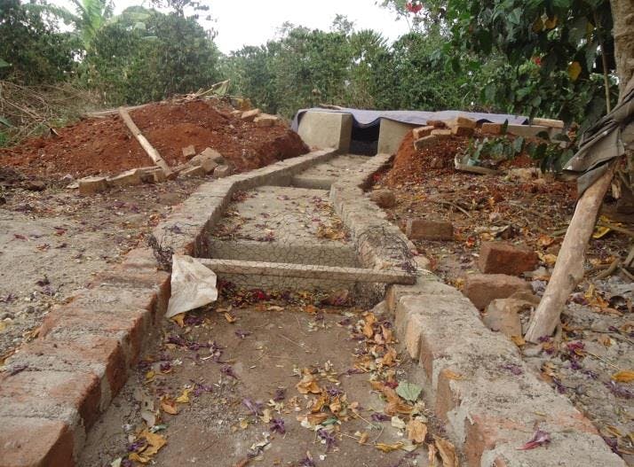 a brick walkway is being built in the middle of a dirt field .