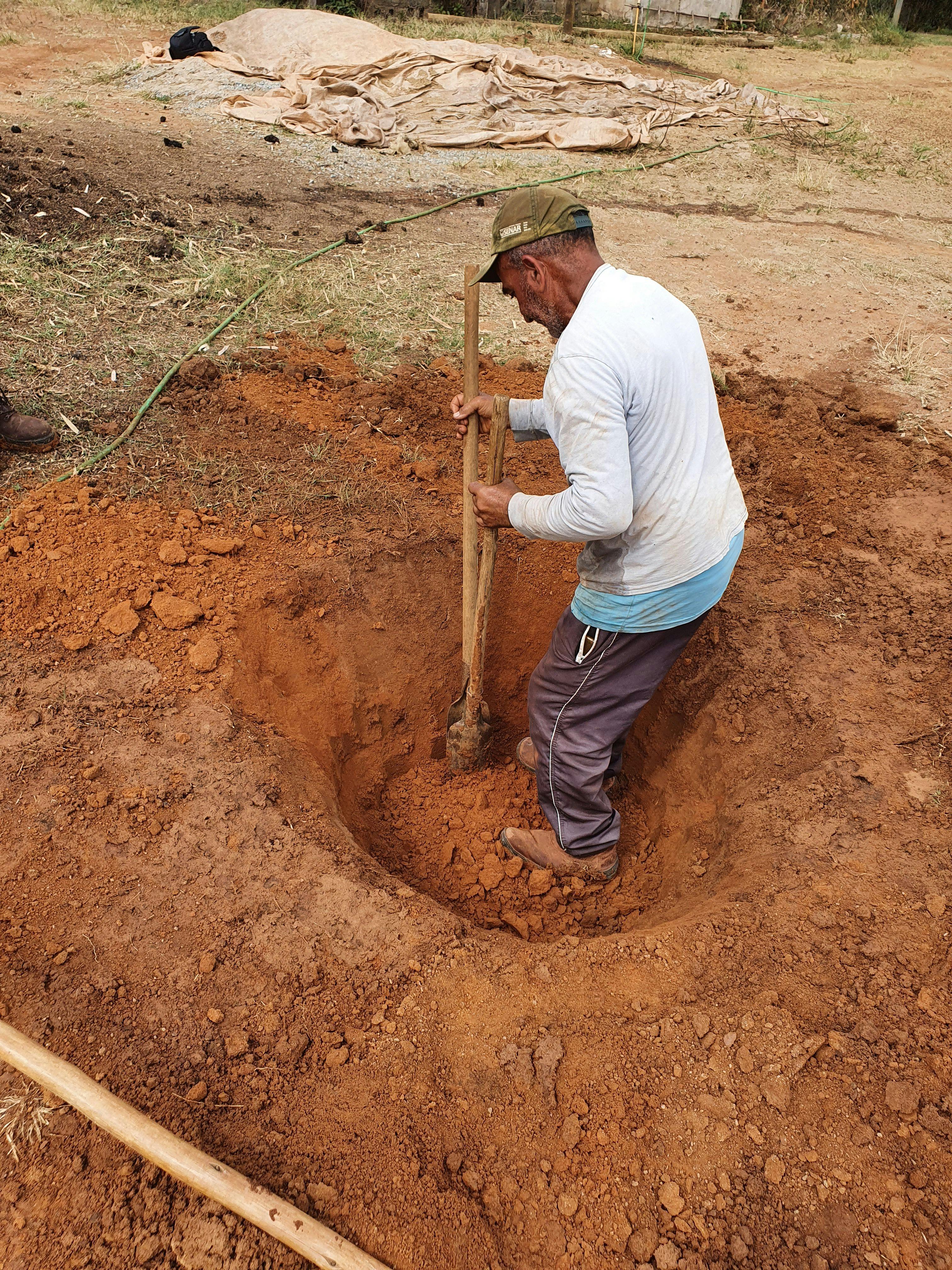 a man is digging a hole in the dirt with a shovel