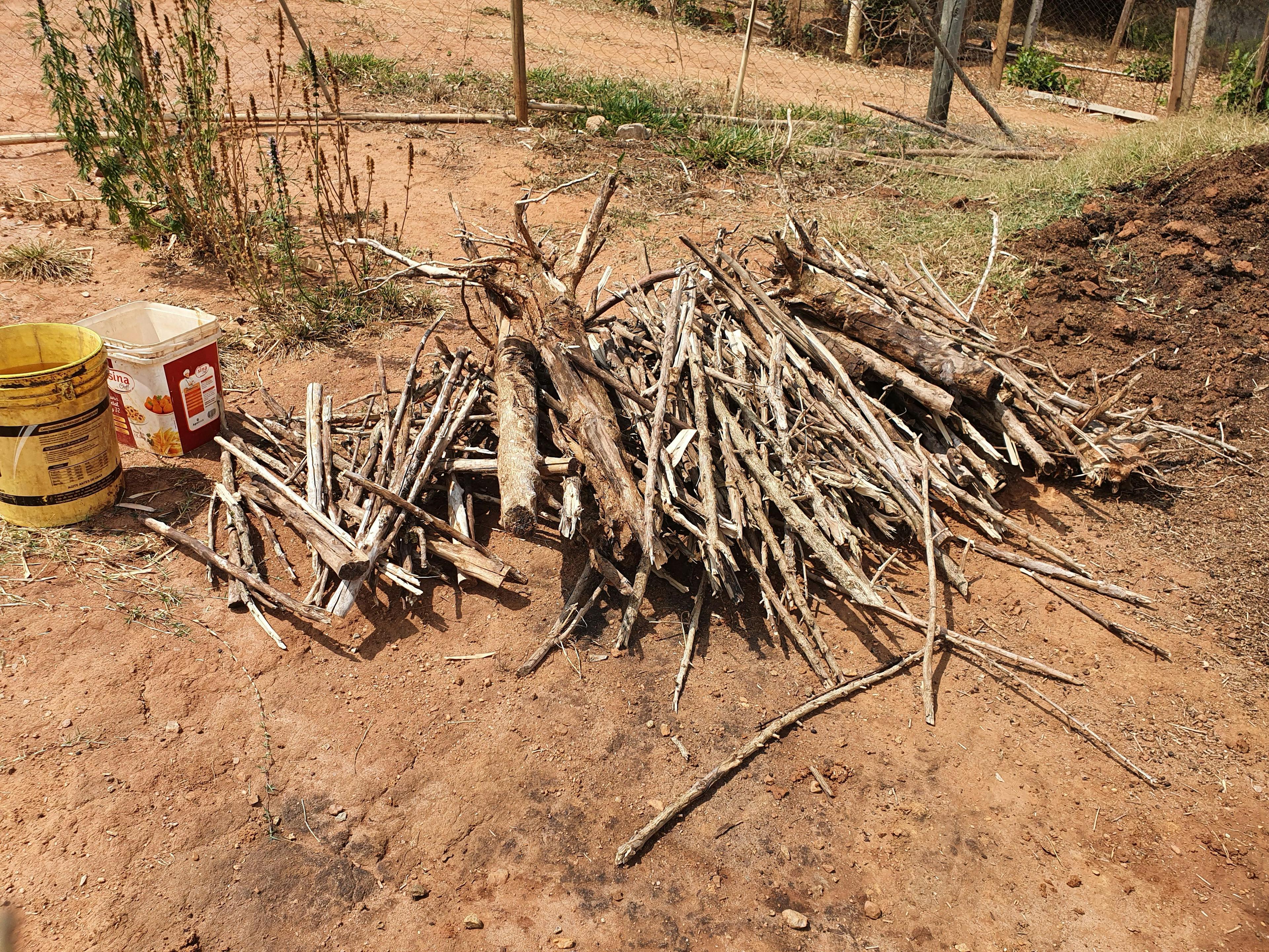 a pile of wood is sitting on the ground next to a yellow bucket .