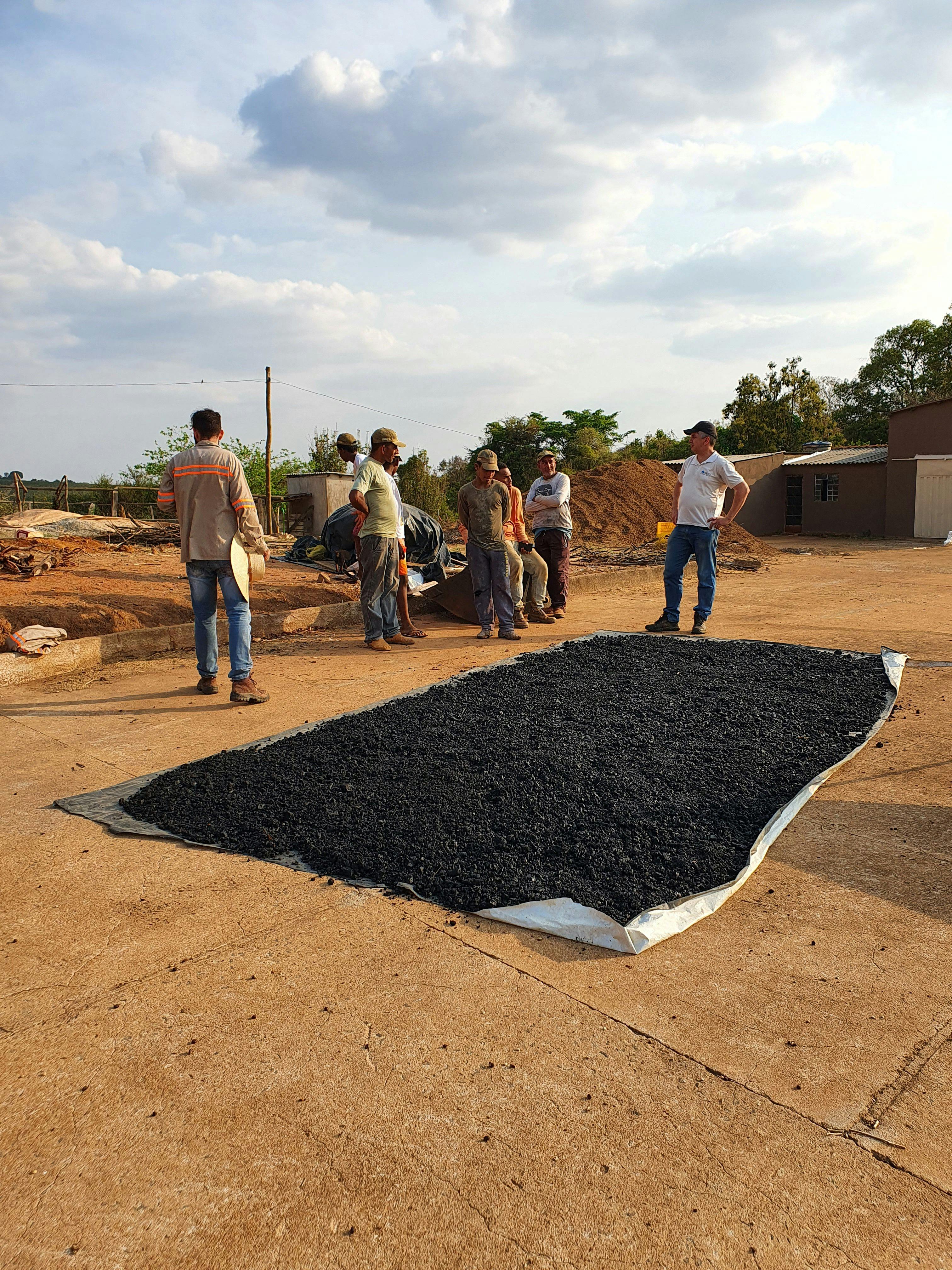 a group of men are standing around a large pile of coal .