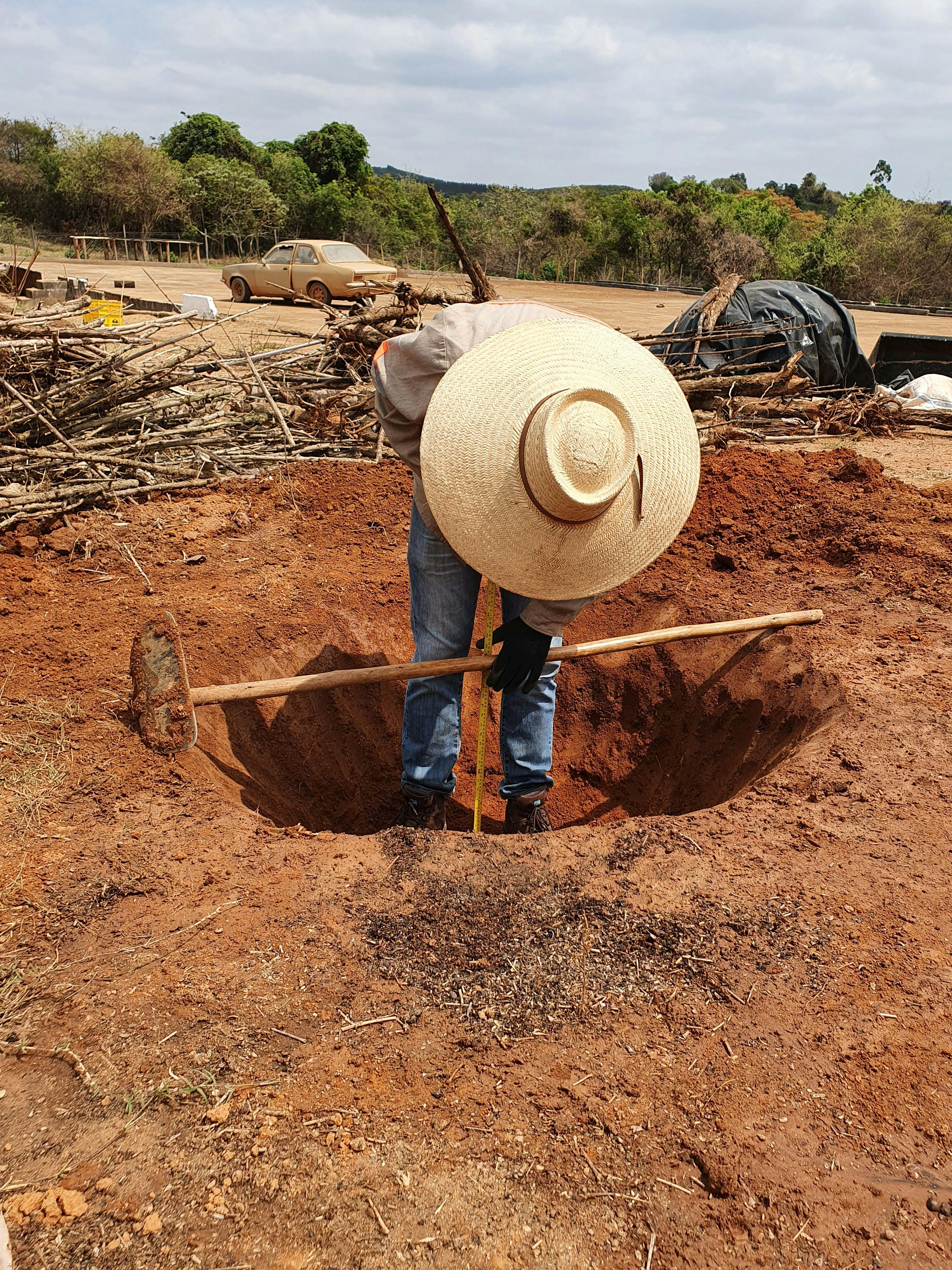 a man wearing a hat is digging a hole with a shovel .