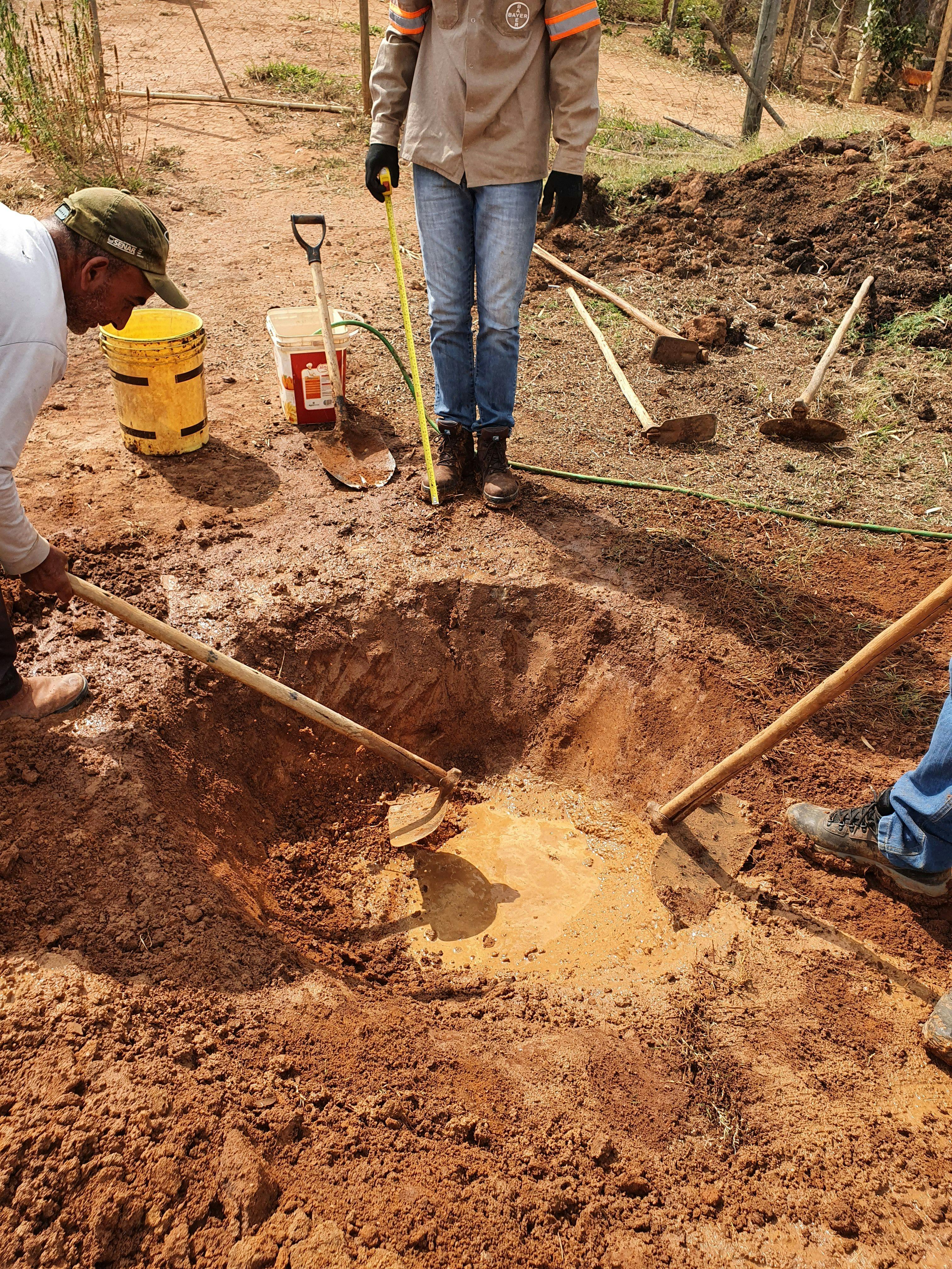 a man is measuring a hole in the ground with a tape measure