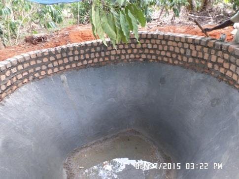 a large hole in the ground filled with water and bricks .